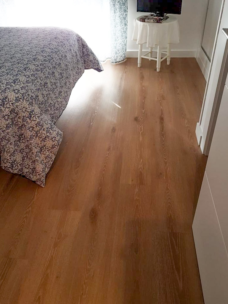 Dormitorio con suelo de madera junto a ventana